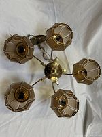 Top view showing five amber glass shades and brass arms