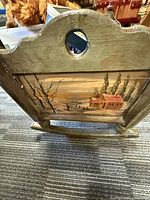 Side view of painted wooden cradle showing landscape artwork
