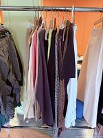Rack with multiple garments including sweaters, cardigans, trousers
