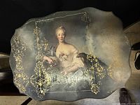 Top view showing portrait, gilt decoration, scalloped edge