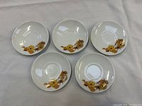 Five matching saucers with floral pattern