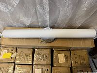 Front view of tubular LED wall sconce on shipping boxes