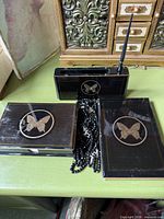 entire set showing address book, note holder, pen holder with pen, and letter stand, all black with gold butterfly medallions