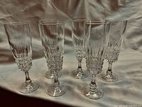 Six cut crystal champagne flutes standing on white fabric