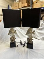 Front view of both brass dolphin lamps with shades