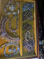 Overall tray view showing rhinestone bib, coordinating pieces, chain clusters, pearl strands