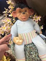 Front view of rubber-faced monkey doll seated, showing face, body, striped waistband
