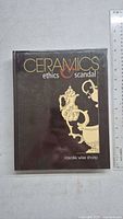 Front cover of the hardcover book 'Ceramics: Ethics & Scandal' with decorative ceramic illustration and title.