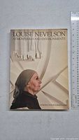 Front cover of the softcover book showing Louise Nevelson in profile with sculptural background and title text.