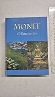 Front cover of the hardcover art book titled 'Monet: A Retrospective' showing colored prints of Monet paintings.