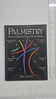 Front cover of the palmistry paperback book, showing colorful illustrated palm lines and title text.