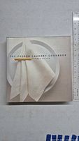 Front cover of The French Laundry Cookbook showing a white napkin and plates.