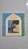 Front cover of the paperback book 'The Perfumed Garden' with decorative blue and gold border and a colorful garden scene illustration with a man on a horse.