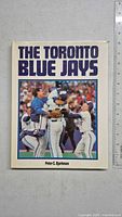 Front cover of the book showing the title, author, and photo of Blue Jays baseball players celebrating.