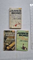 Front covers of three vintage James Bond paperbacks: 'On Her Majesty's Secret Service,' 'Octopussy,' and 'You Only Live Twice' by Ian Fleming, published by Pan Books. Condition shows some use and age.