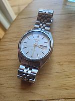 Oblique view of watch head and bracelet laid flat on wood surface