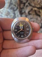 Front view of the watch showing black dial, Soviet emblem, numerals and hands.