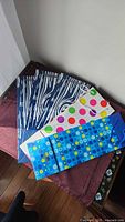 5 bottle-sized gift bags with blue, white, and colorful dot designs displayed on a cloth surface.