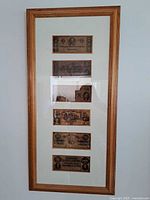 Framed collection of six Confederate currency bills in wooden frame with glass, arranged vertically with white matting.