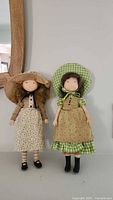 Front view of two vintage Holly Hobby dolls standing next to each other, showing clothing and hair details.