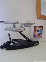 Side view of the USS Enterprise Star Trek telephone next to the VHS tape.