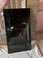 Front view of the 55 inch flat screen TV showing the screen damage with reflective surface and part of the room visible.