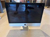 Front view of Apple iMac showing screen and Apple logo on aluminum body.