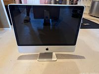 Front view of Apple iMac computer with black screen and silver aluminum body.