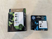 Two sealed HP ink cartridge packages. Left package includes one black and one tri-color cartridge. Right package includes a single black cartridge.