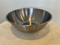 Single large stainless steel mixing bowl on a cloth surface with neutral background.
