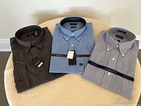 Three folded men’s dress shirts displayed on a surface showing colors and patterns