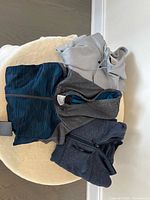 Image showing three men’s sweatshirts laid out: gray Under Armour hoodie, dark blue Under Armour zip-up, and dark gray North Face zip-up with chest pocket.