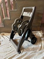 Mobile garden hose reel cart shown angled to display front and side, highlighting wheels, crank handle, and support frame.