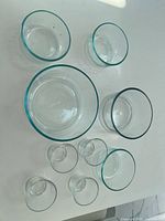 Seven clear glass bowls arranged on a white surface. 3 larger bowls of varying sizes in the back, 4 smaller bowls placed in front.