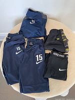 Photo shows four pairs of kids sweatpants and one jacket, all sporty style, navy and black colors.