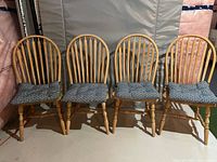 Four wooden chairs with curved spindle backs and turned legs, each with a blue and white patterned seat cushion.
