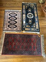 Three wool rugs on hardwood floor showing size and pattern differences.