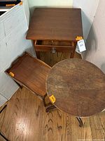 Photo showing all three wooden vintage side tables on hardwood floor with visible age-related surface wear.