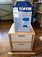 Photo of boxed Top Fin Aquascene 2 aquarium kit on top of wooden storage cube unit with two beige fabric storage drawers.