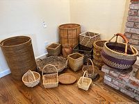 Photo showing full assortment of baskets arranged on wooden floor near a brick fireplace and corner wall.