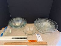 Group view of two sets of clear glass mixing bowls, from smallest to largest sizes, alongside three small fluted dessert bowls, with measuring rulers for scale.