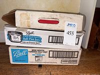 Three stacked boxes of Ball half-pint wide mouth tapered jars in original packaging, one box with a red handle.