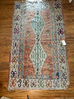 Full view of the Kilim rug displaying the overall geometric design and colors on a wooden floor.