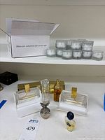 View of assorted perfume bottles including Chanel No. 5, Norrell, and multiple skincare cream pots in small frosted glass jars, arranged on two shelves with cardboard box marked 'Skincare solutions for every age'.