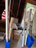 Photo showing several PVC roll-up shades in tubes, rolls of screening, curtain rods, and boxes containing other items.