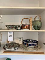 Overview of top shelf with two bamboo-handled teapots and rectangular floral bowl
