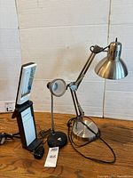 View of all three lamps on wooden surface against cardboard background, showing different styles and sizes of the task lights.