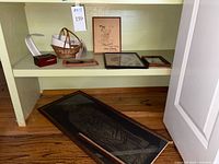 Shelf with music box, paper music strips, wicker basket with music strips, framed Disney drawing, signed photo, and smaller framed photos.