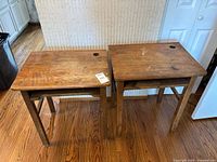 Front view of two wooden school desks placed side by side showing worn surfaces with scratches and water stains.
