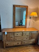 Full view of dresser and mirror showing wood finish, drawer and door layout, and mirror frame.